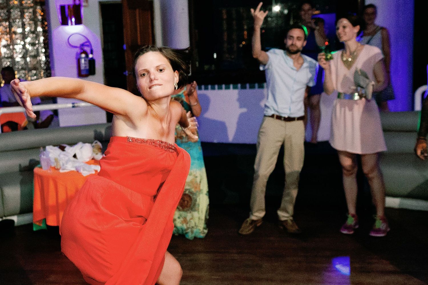A bridesmaid in a coral dress performs an expressive dance at the reception.