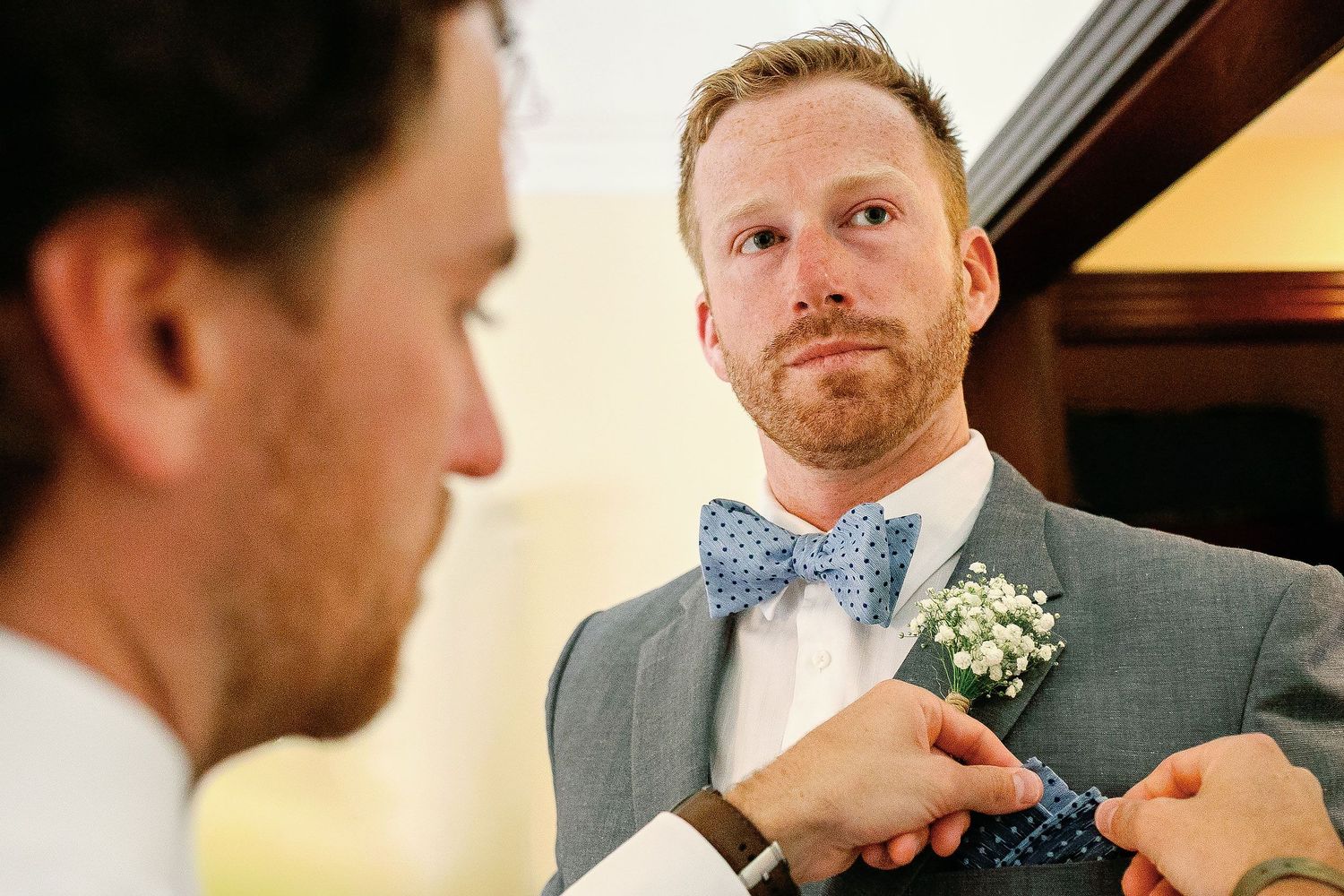 A groomsman adjusts Alan’s pocket square and boutonniere during his wedding preparation at Riu Palace Riviera Maya in Playa del Carmen.