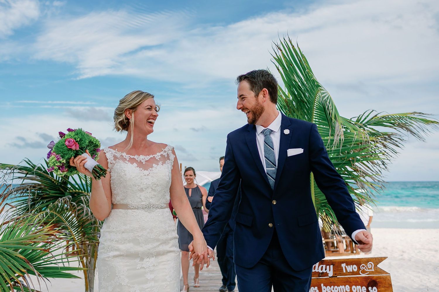 Newly married Ashley and Matt walk hand in hand from their beach ceremony beside the Caribbean.