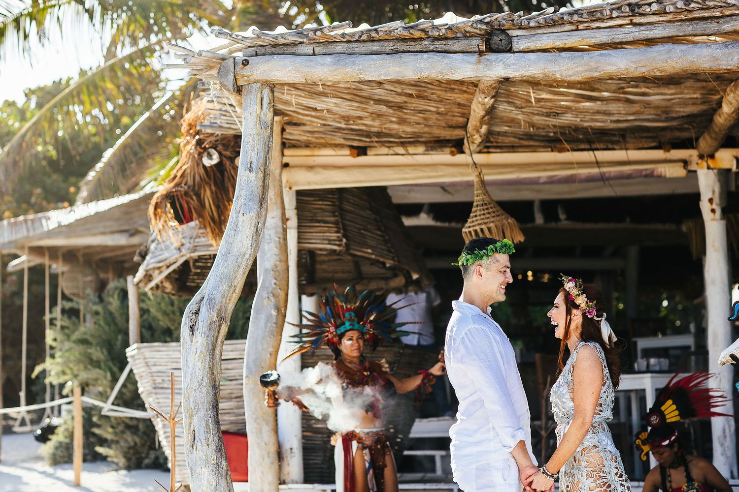 Sarah and Evish hold hands as ceremonial smoke drifts behind them.