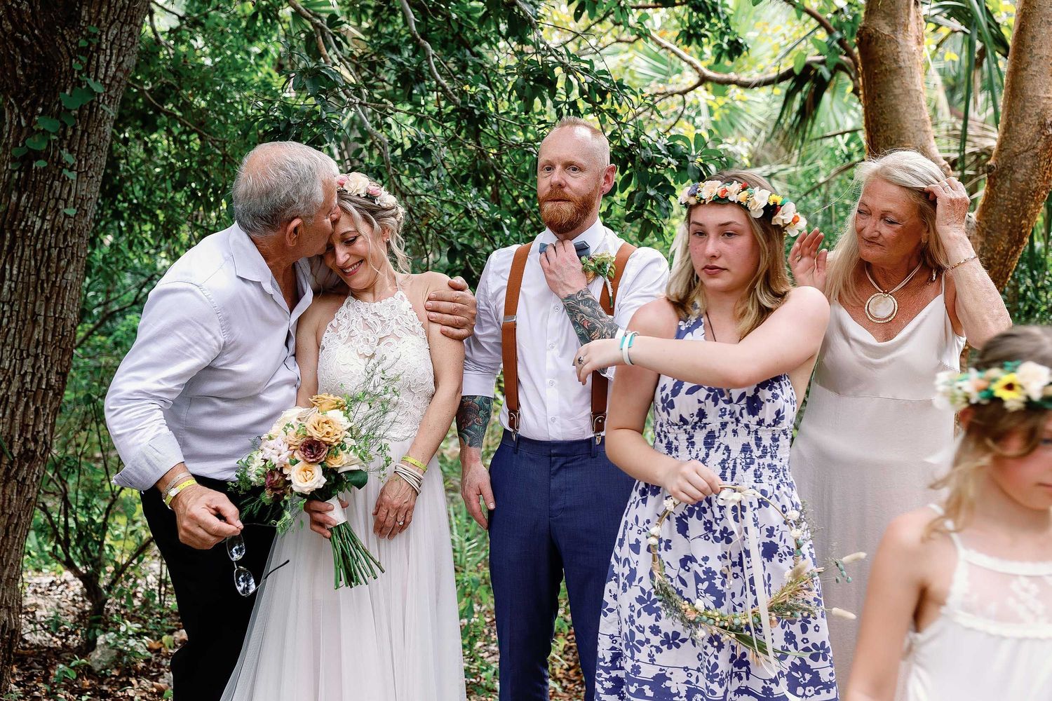 A loved one kisses Veronica’s forehead as family gathers around the newlyweds after their intimate cenote wedding ceremony near Playa del Ca