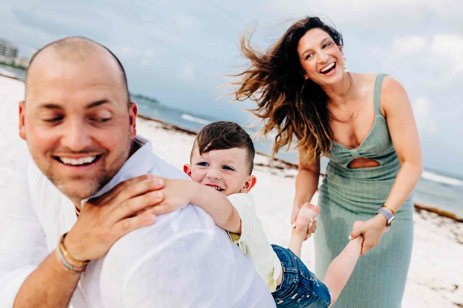 Parents and child sharing joyful moments during a beach photography session