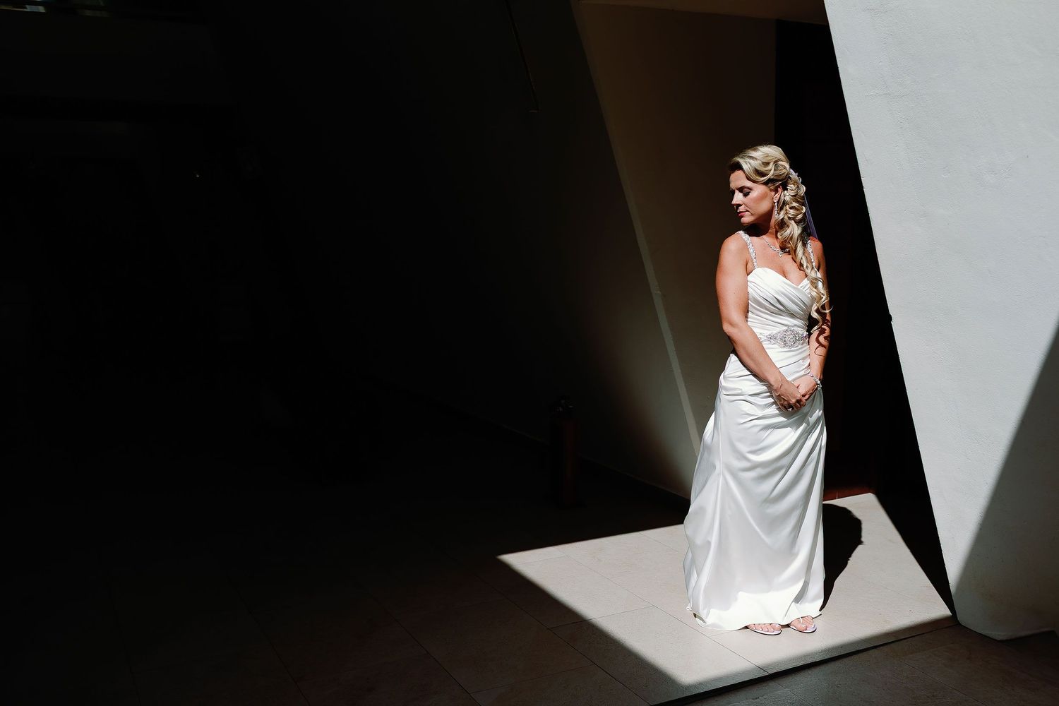 Dramatic portrait of Carly standing in sunlight in her wedding gown