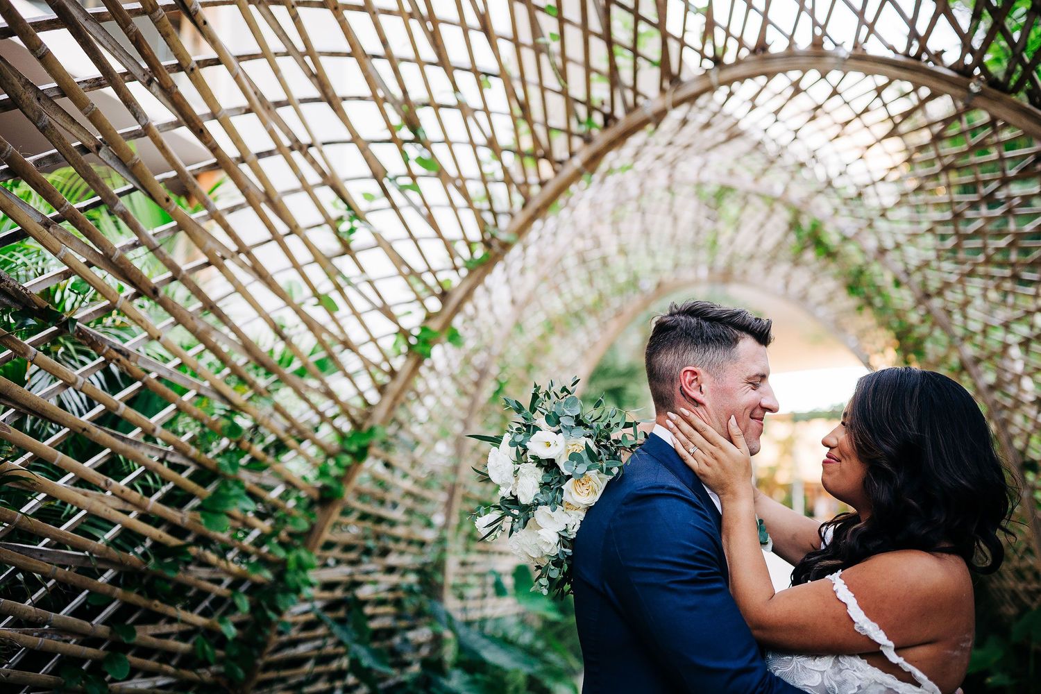 Bride and groom smiling together inside a woven bamboo tunnel during their wedding portrait session at Secrets Moxché Playa del Carmen.