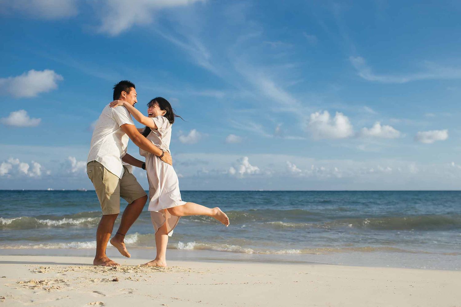 Fun Cancun engagement photography with joyful couple dancing barefoot on a Caribbean beach in Riviera Maya Mexico