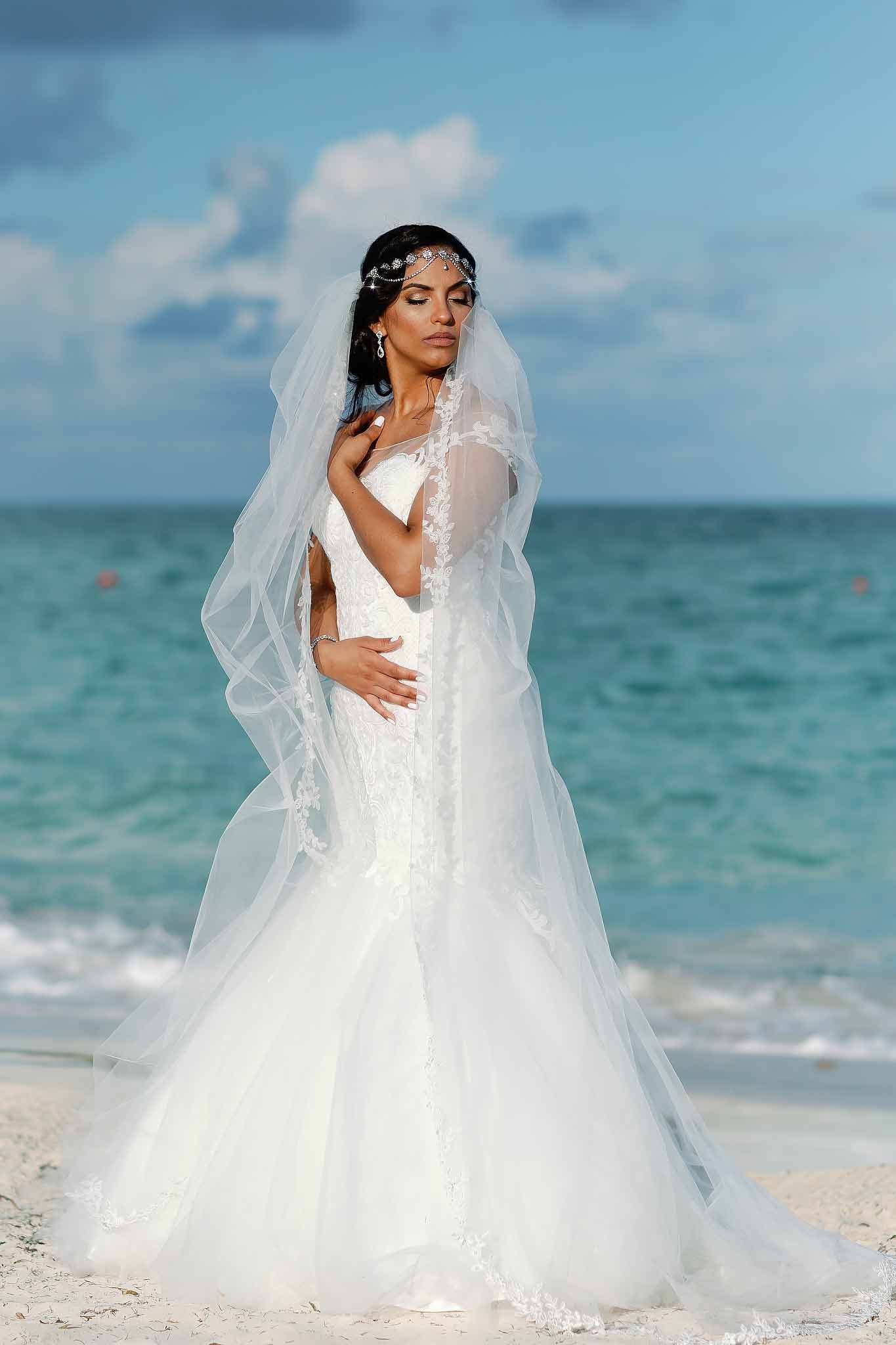 Luxury Cancun bride portrait featuring a wedding dress and veil on a white sand Caribbean beach.