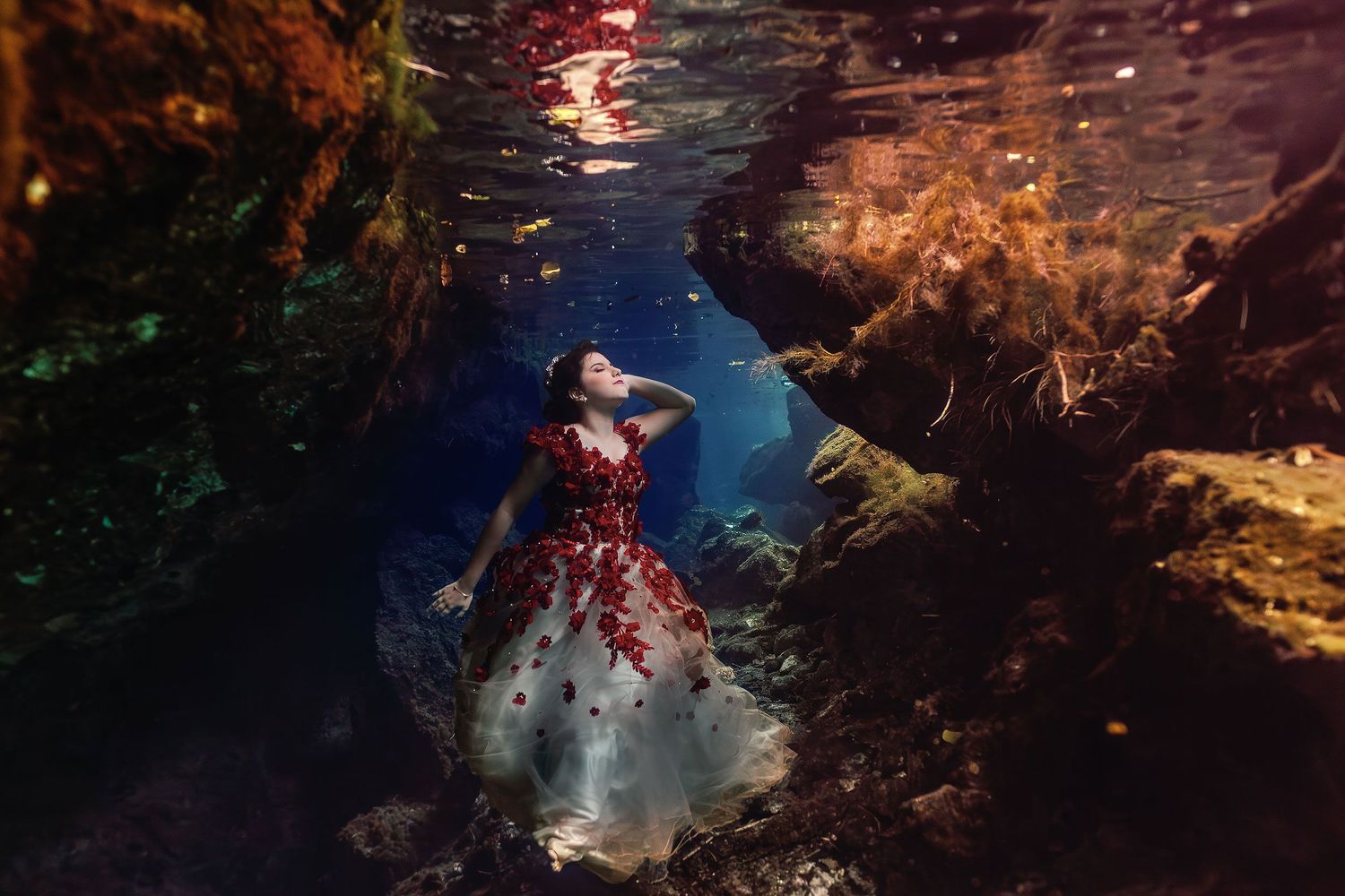 Underwater quinceañera portrait in a cenote near Playa del Carmen featuring an elegant red and white gown surrounded by crystal-clear water