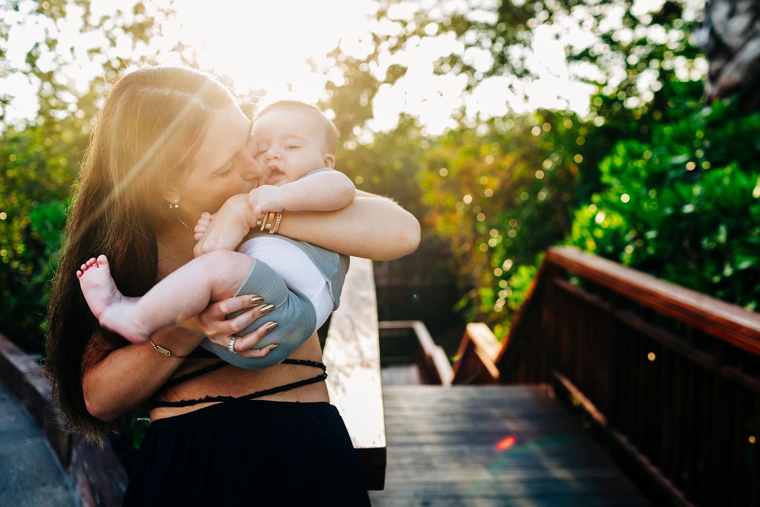 Mother kissing her baby during golden hour family photography session at Fairmont Mayakoba Playa del Carmen.
