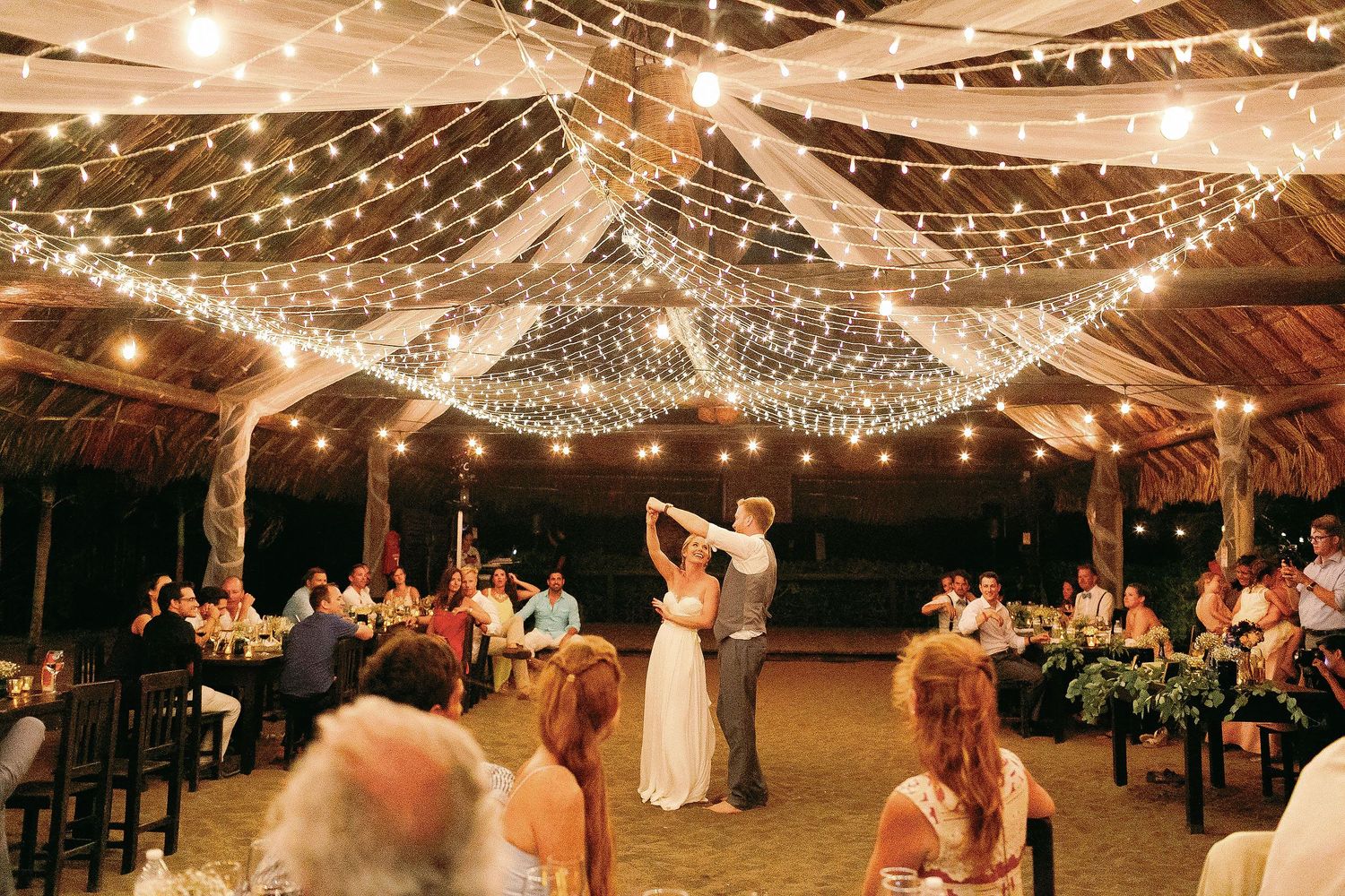 Cressida and Alan sharing their first dance beneath string lights during their private Riviera Maya wedding reception.