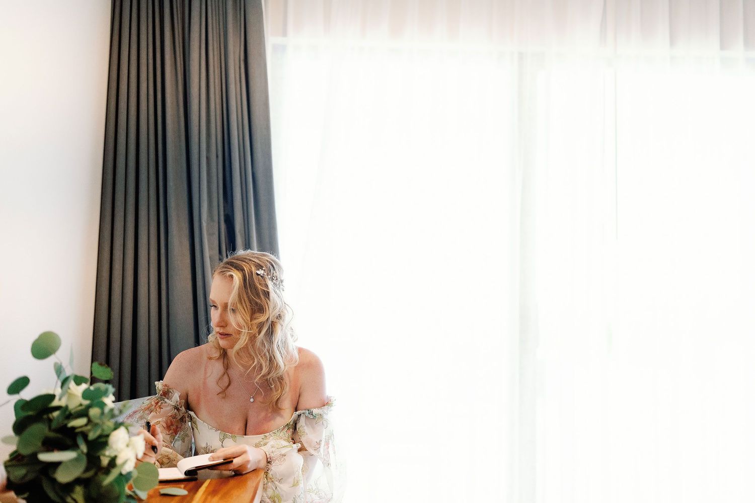Autumn writing in a notebook while wearing her floral gown before her Dreams Sapphire beach wedding.