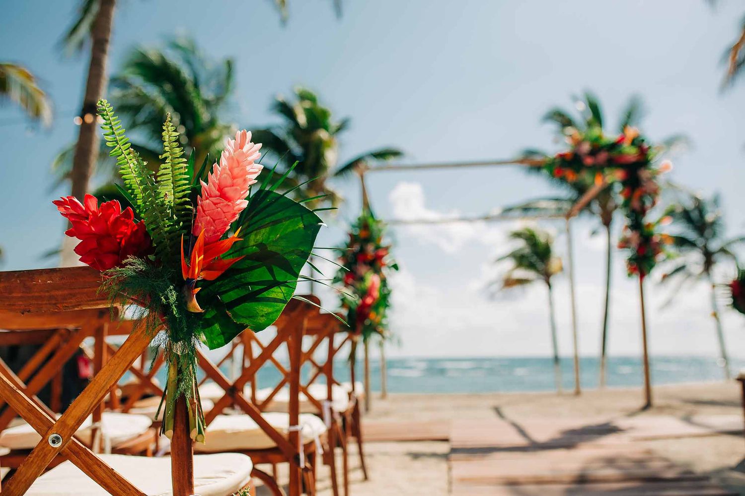uxury Cancun beach wedding setup with tropical flowers, palm trees, and oceanfront ceremony backdrop