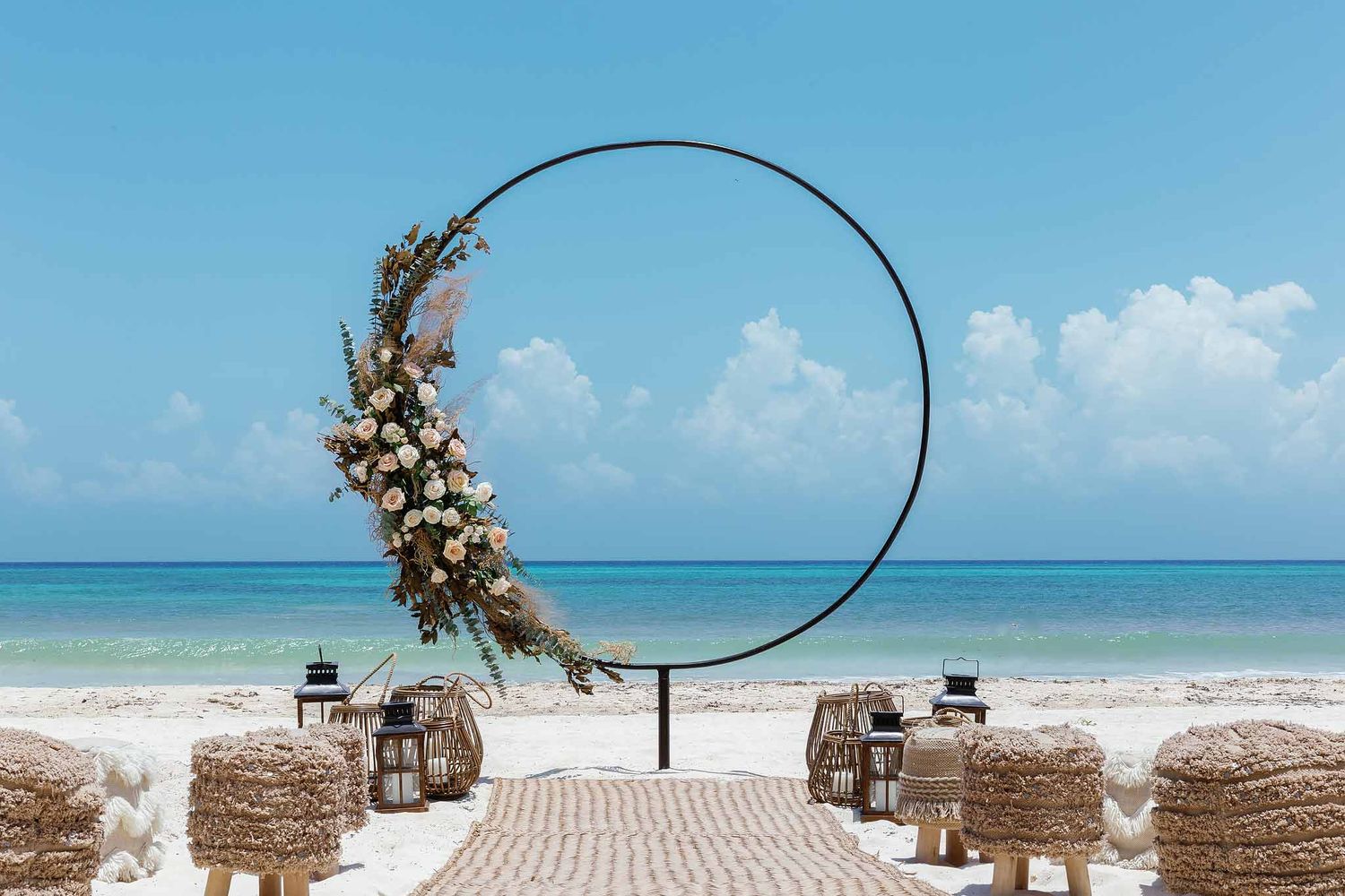 Tulum beach wedding ceremony setup with circular arch, boho floral arrangement, and Caribbean ocean view in Riviera Maya