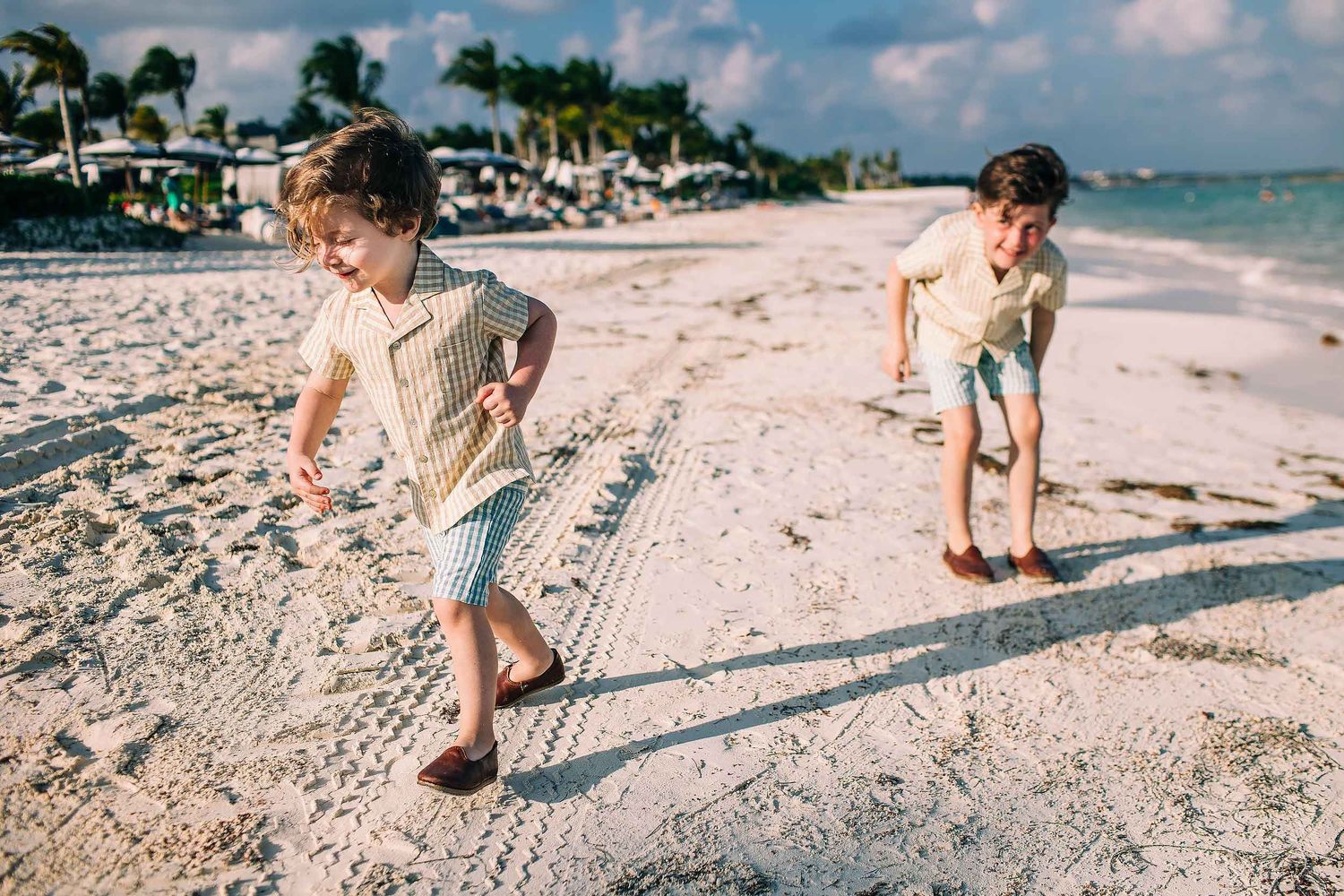 Children running barefoot on the beach during a playful family photo session at Fairmont Mayakoba Riviera Maya.