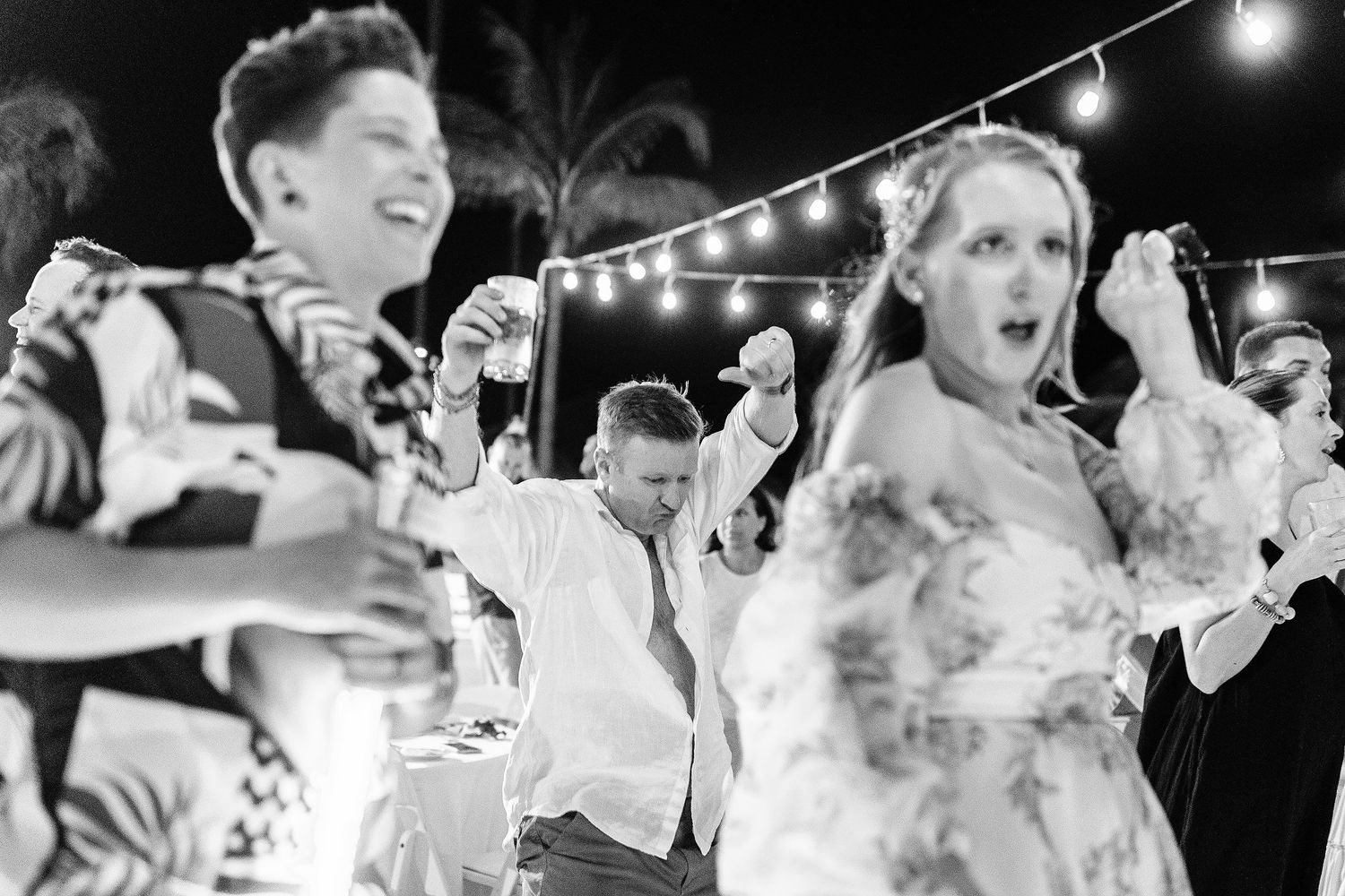 Wedding guests dancing beneath string lights during Autumn and Brian’s beach reception at Dreams Sapphire.