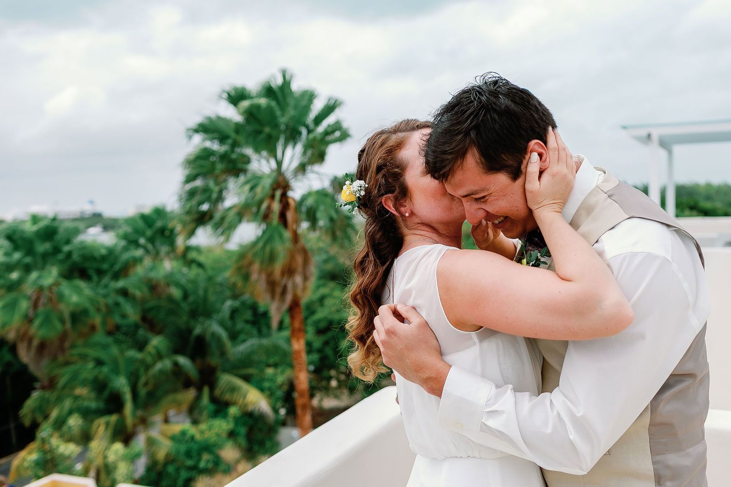 Li embraces Carlos after their first look, with palm trees surrounding the rooftop terrace.