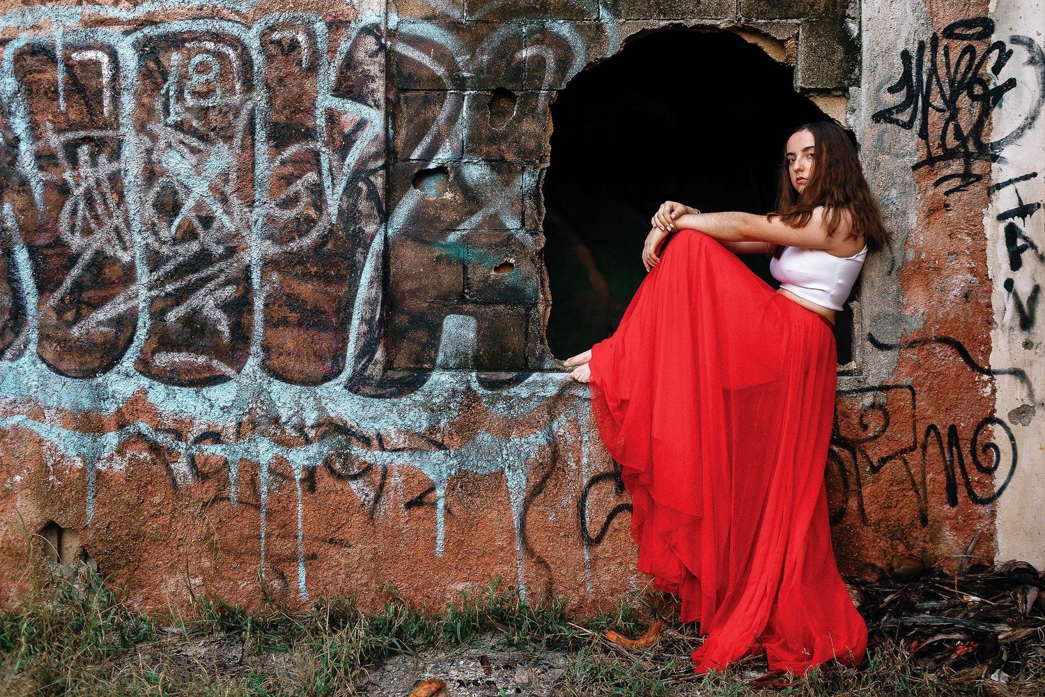 Senior portrait session in Playa del Carmen featuring a flowing red skirt and colorful urban art wall for an editorial look.