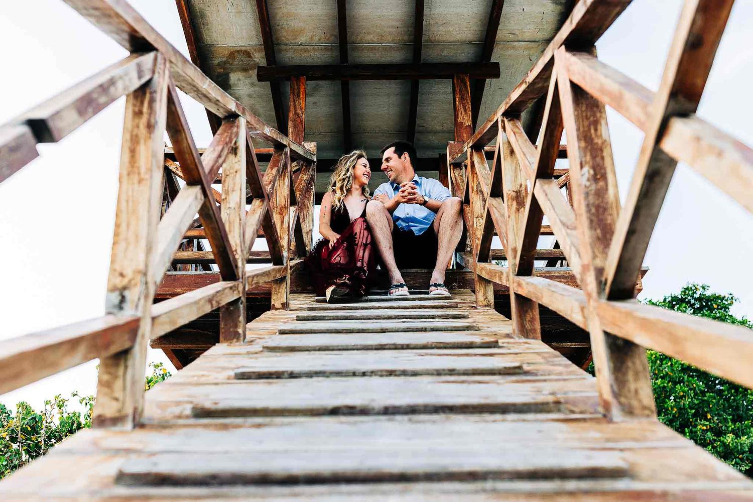 Couple sitting on a wooden beach lookout during their Punta Esmeralda engagement photography session.