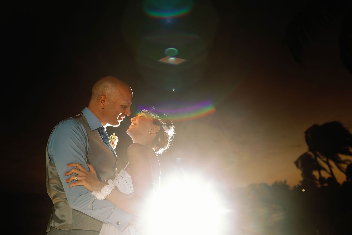 Juliana and Tom share a romantic moment in a dramatically lit nighttime beach portrait.