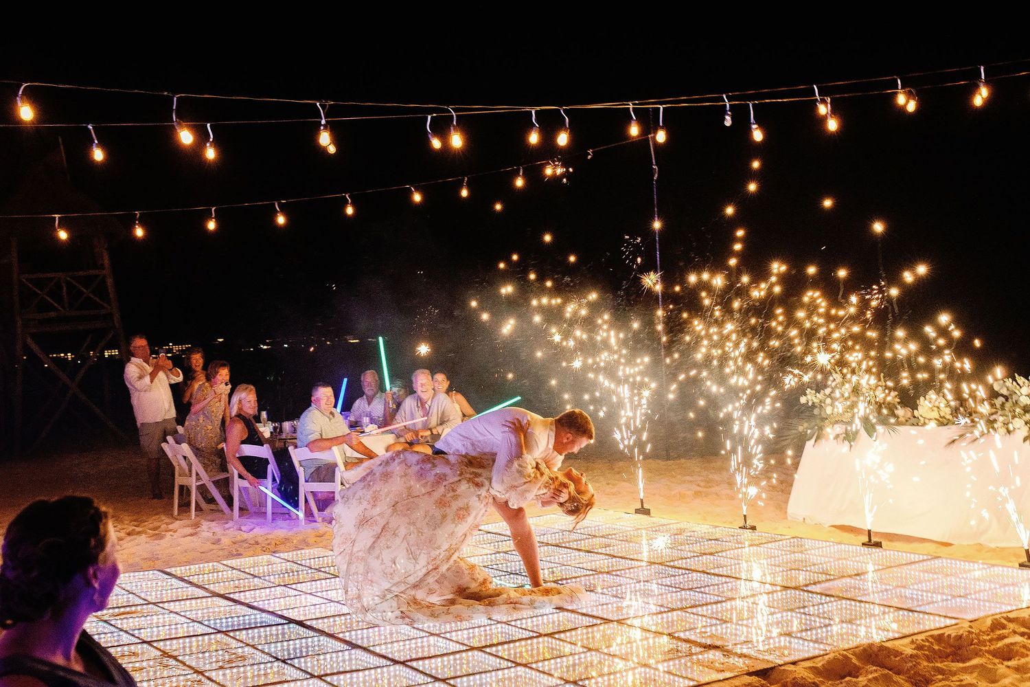 Autumn and Brian performing a dip during their beach reception first dance surrounded by cold sparks.