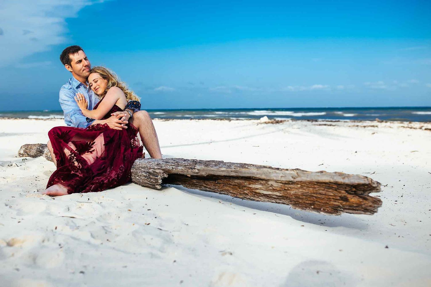 Couple embracing on the white sand beach during a romantic engagement session in Punta Esmeralda Playa del Carmen.