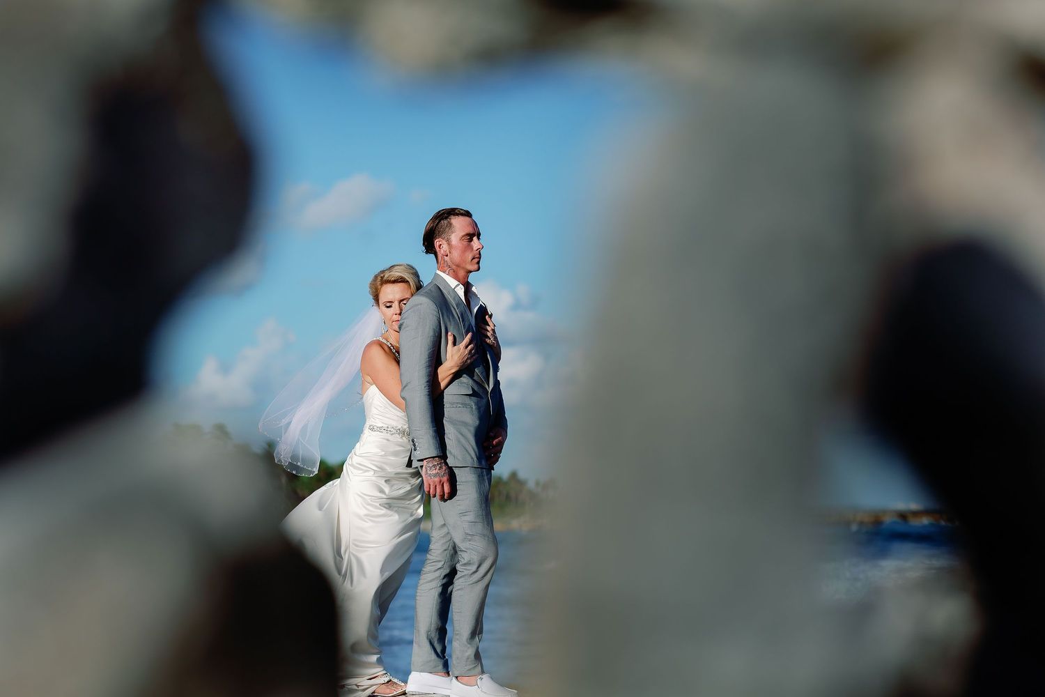 Carly embracing Scott during their newlywed portraits beside the sea
