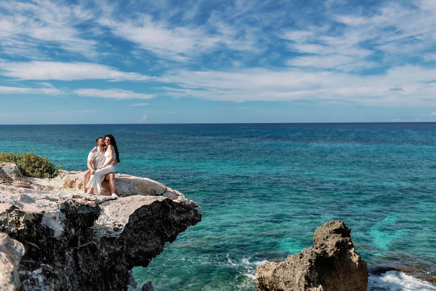 Sam kisses Alexia as they sit together on a cliff above the Caribbean at Punta Sur.