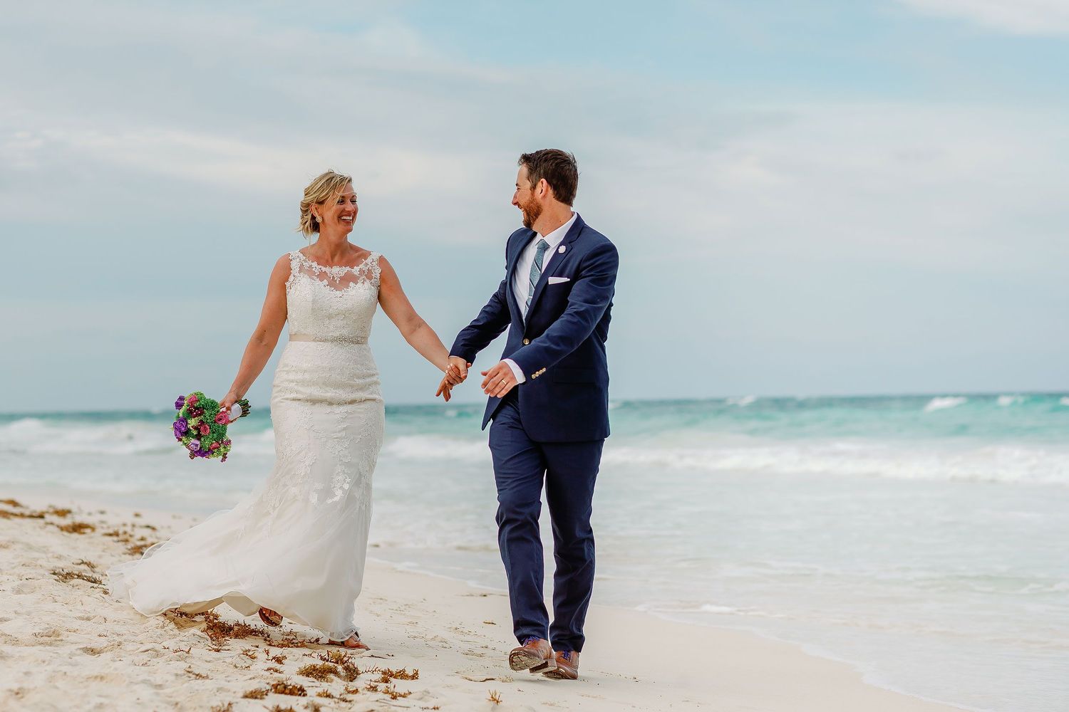 Ashley and Matt walk hand in hand along the Tulum shore after their wedding ceremony.