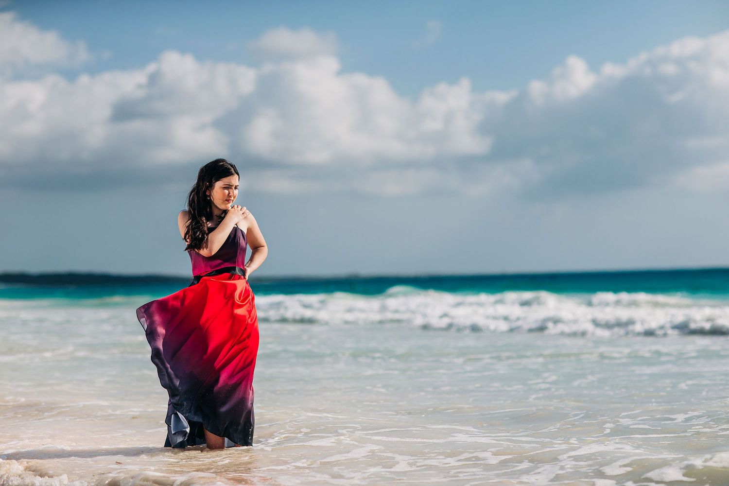 Senior portraits in Cancun with a vibrant red dress, white sand beach, and the turquoise waters of the Caribbean Sea.