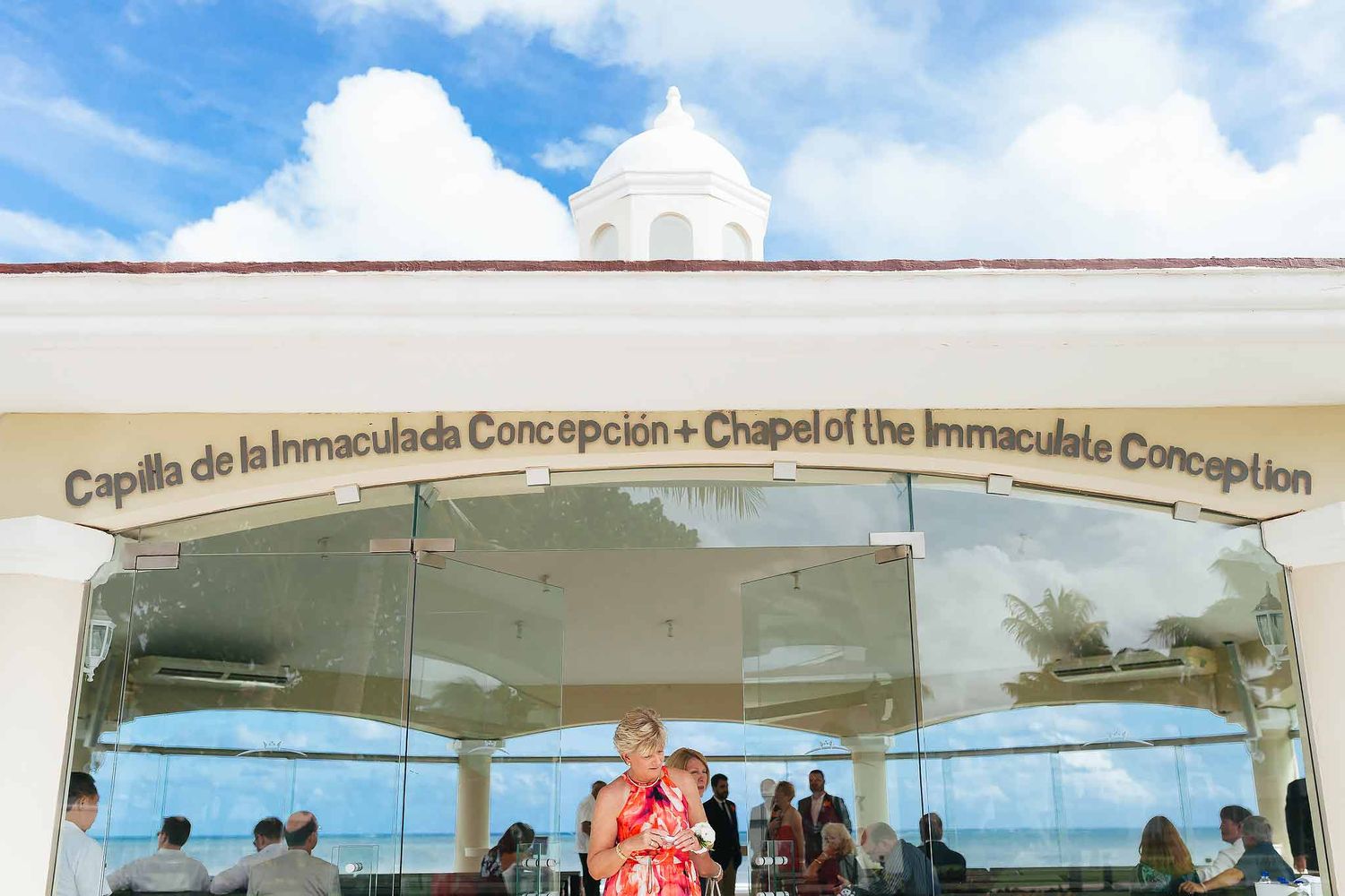 Entrance of Chapel of the Immaculate Conception at Moon Palace Cancun with glass doors and Catholic wedding guests