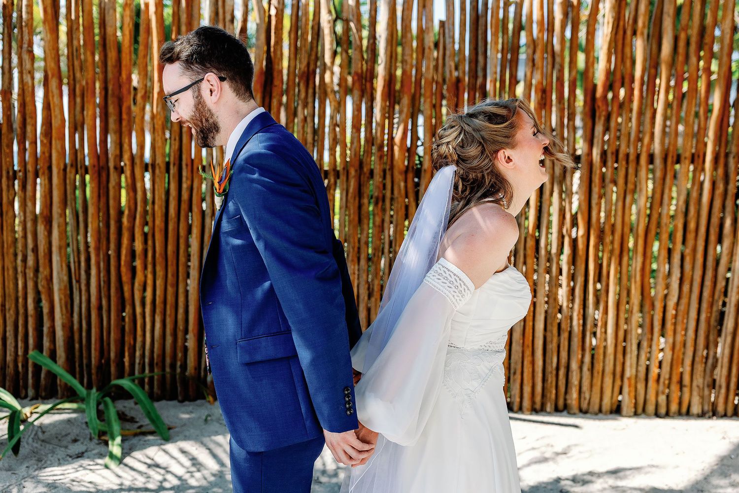 Nicole and Thomas stand back-to-back holding hands during their first touch before their Blue Venado wedding ceremony in Playa del Carmen.