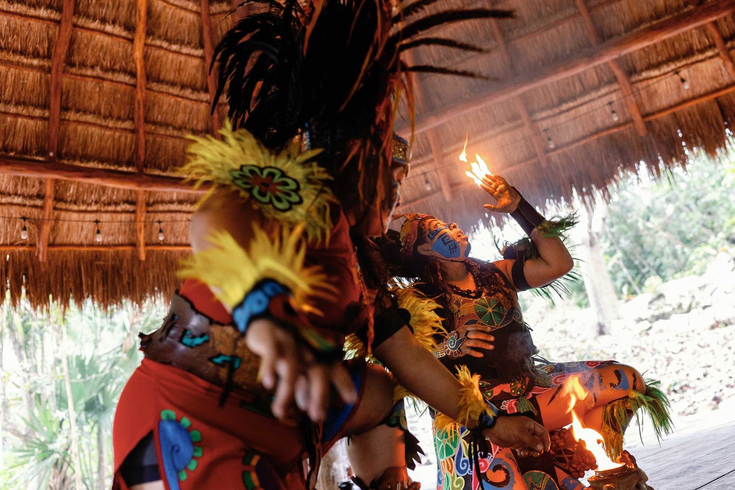 Maya performers presenting a fire performance beneath a traditional palapa at the end of Jeff and Veronica’s Cenote Hats’uts wedding.