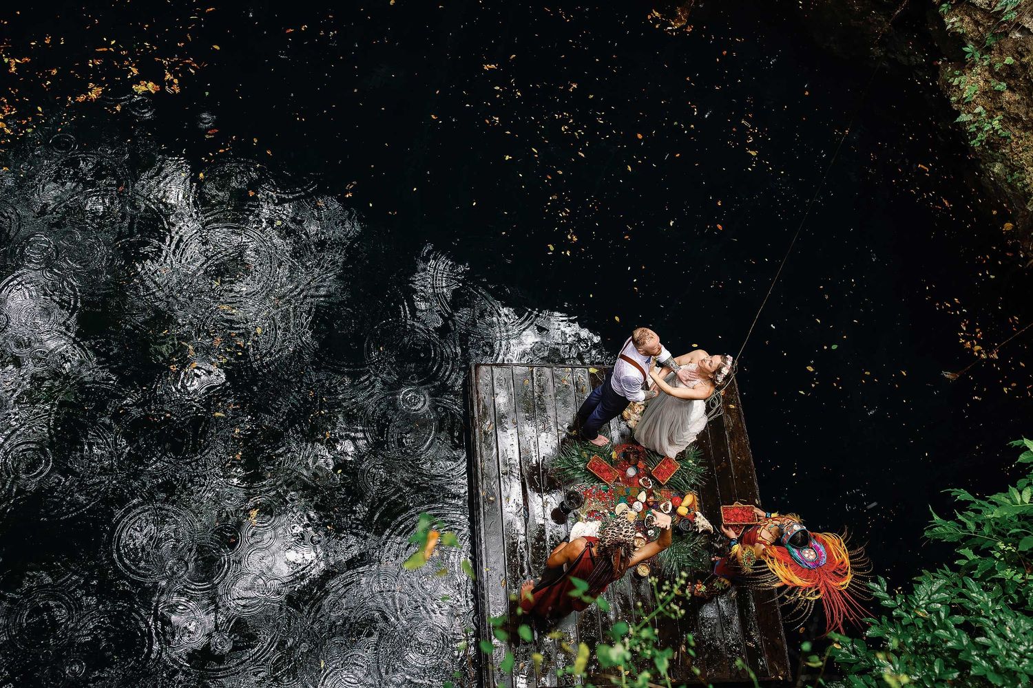 Overhead view of Jeff and Veronica during their Maya wedding ceremony on a wooden platform surrounded by the water of Cenote Hats’uts near P