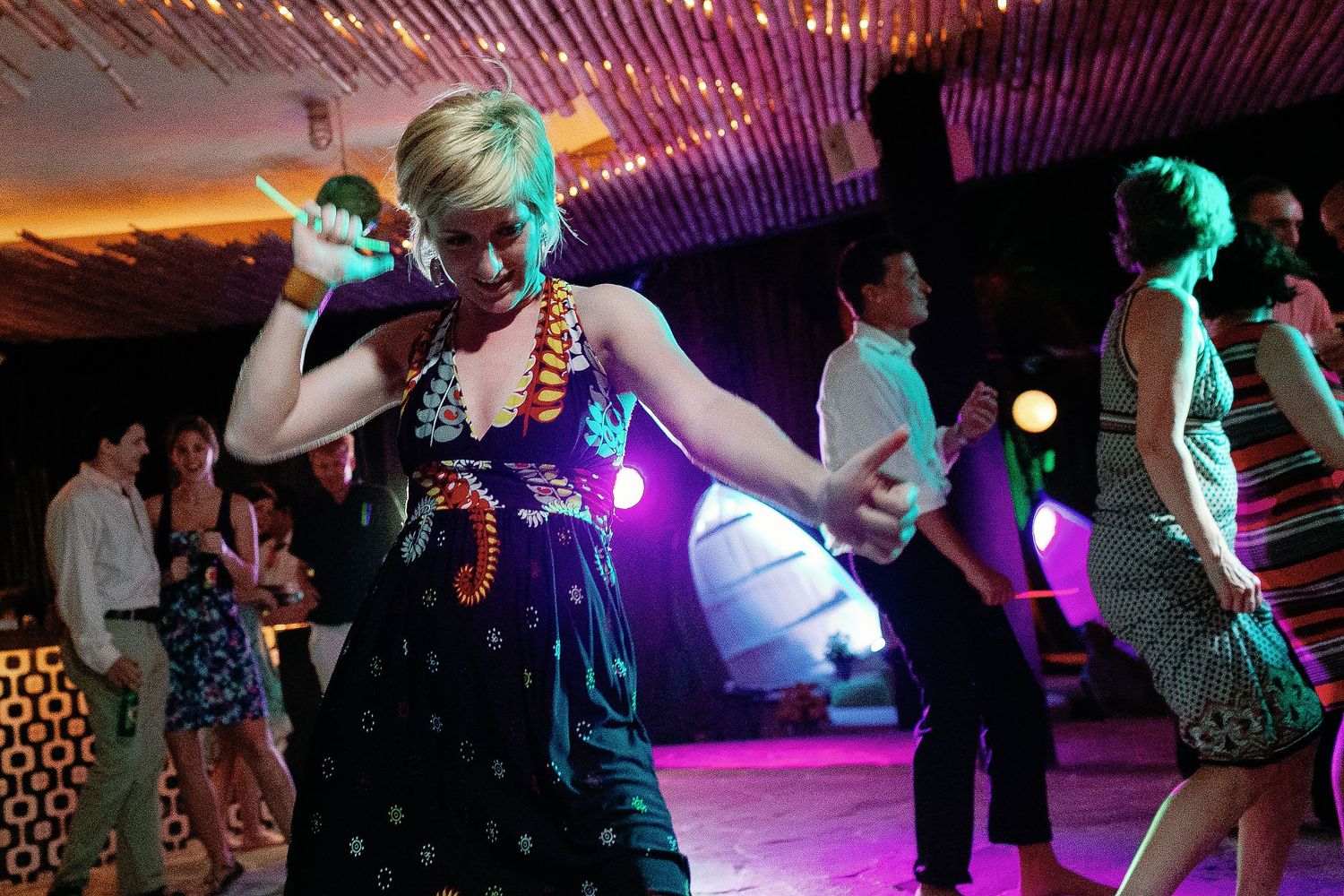 A wedding guest dances beneath colorful lights during the Playa del Carmen reception.