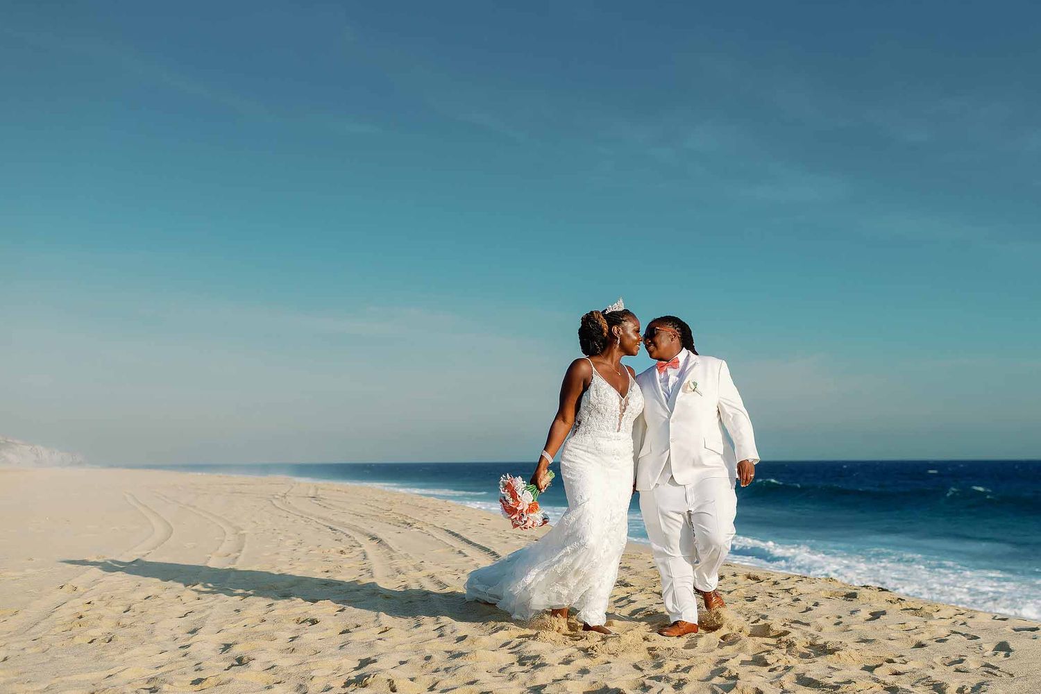 Romantic lesbian wedding couple walking on the beach in Playa del Carmen during a destination wedding in Mexico.