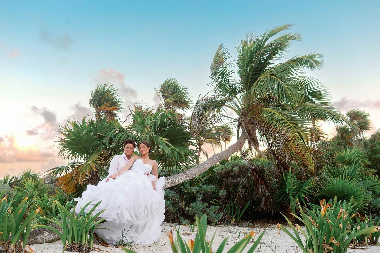 Romantic lesbian wedding portrait surrounded by tropical palm trees in the Riviera Maya during a destination wedding.