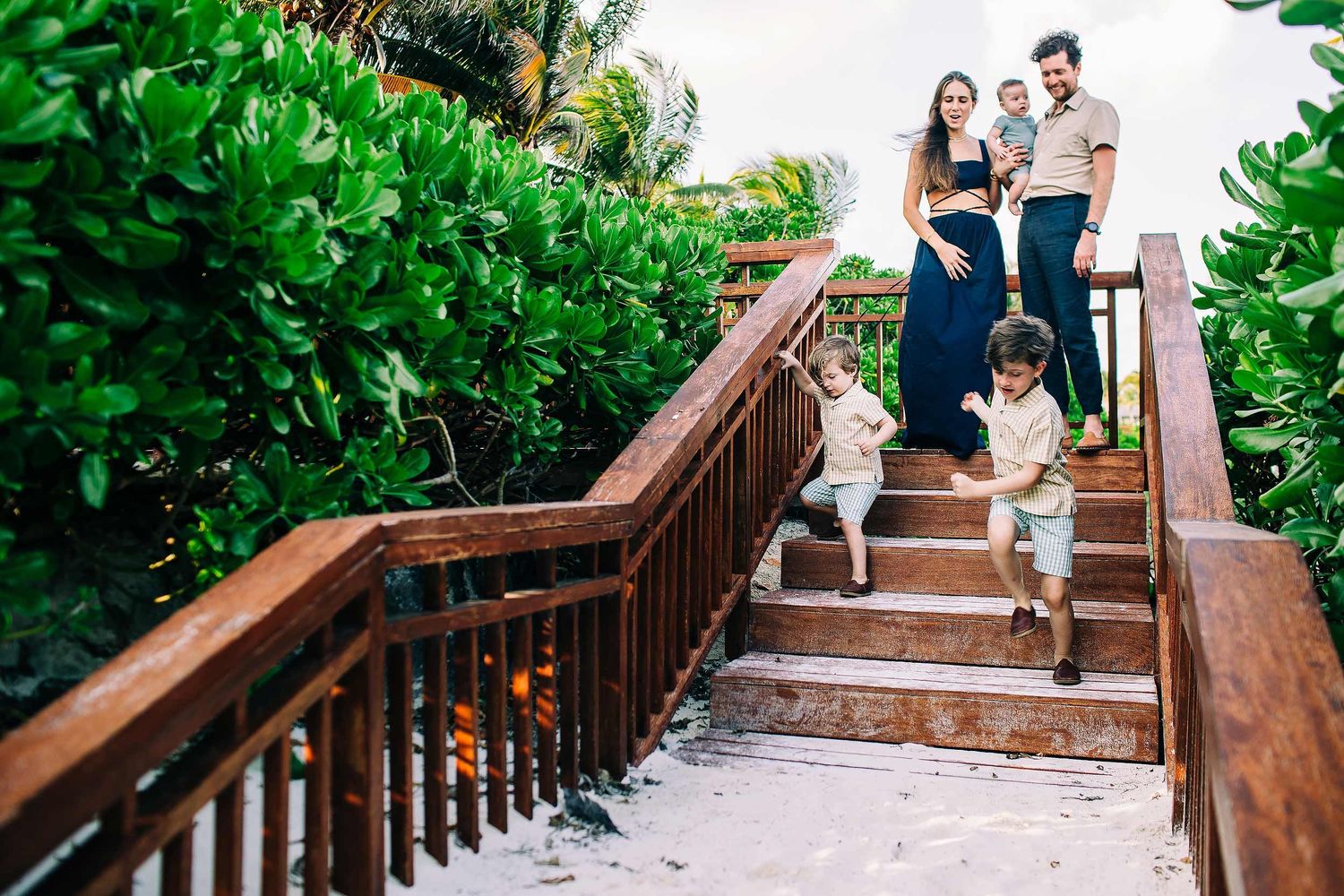 Family exploring the wooden pathways of Fairmont Mayakoba during a Riviera Maya family session.
