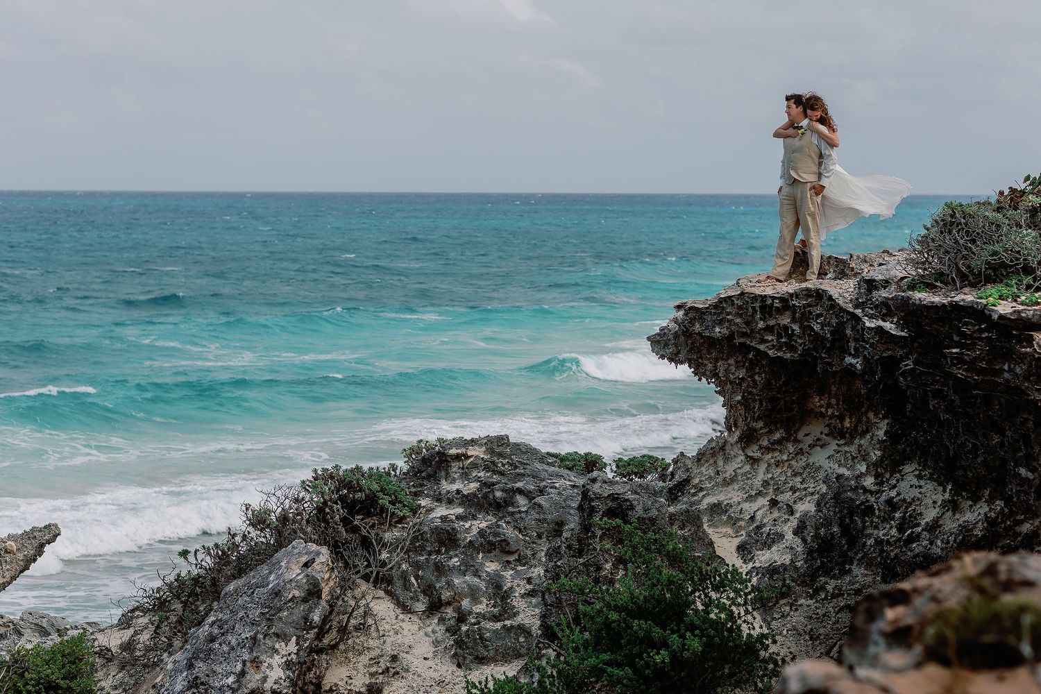 Li wraps her arms around Carlos on a cliff above the turquoise Caribbean Sea in Isla Mujeres.