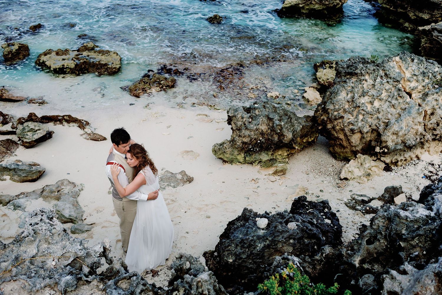 Overhead portrait of Li and Carlos embracing in a small rocky cove on Isla Mujeres.