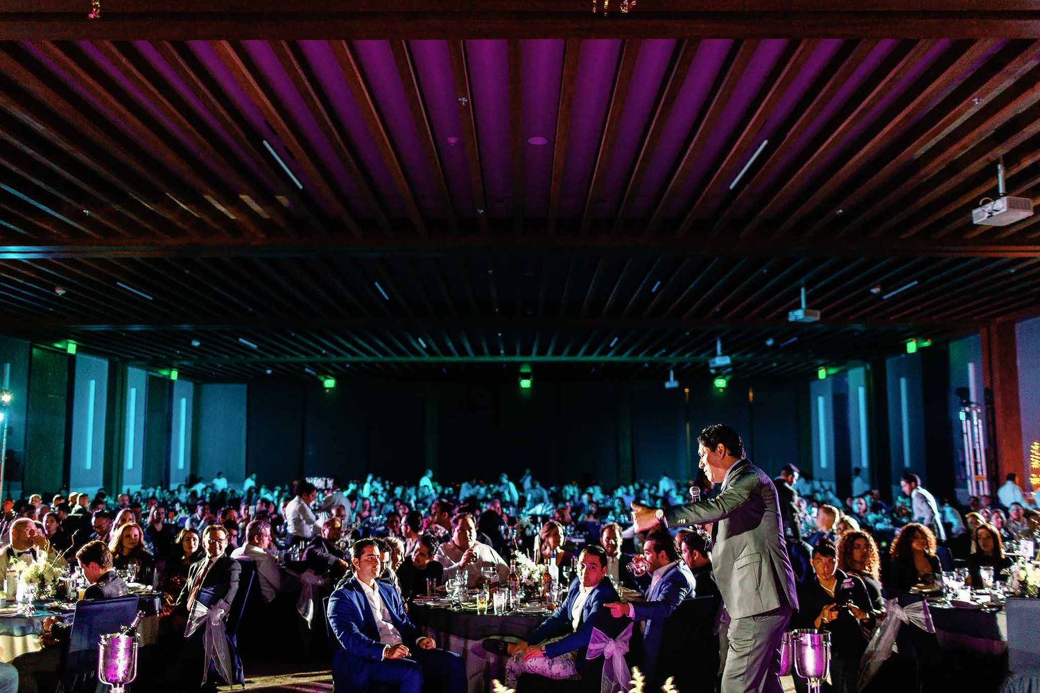 Luxury corporate gala event in Cancun with live speaker presenting to large audience in elegant venue