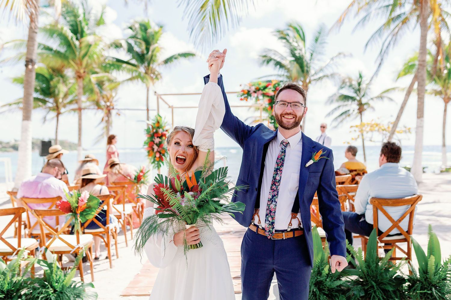 Nicole and Thomas raise their joined hands in celebration after their intimate beach wedding ceremony at Blue Venado in Playa del Carmen.