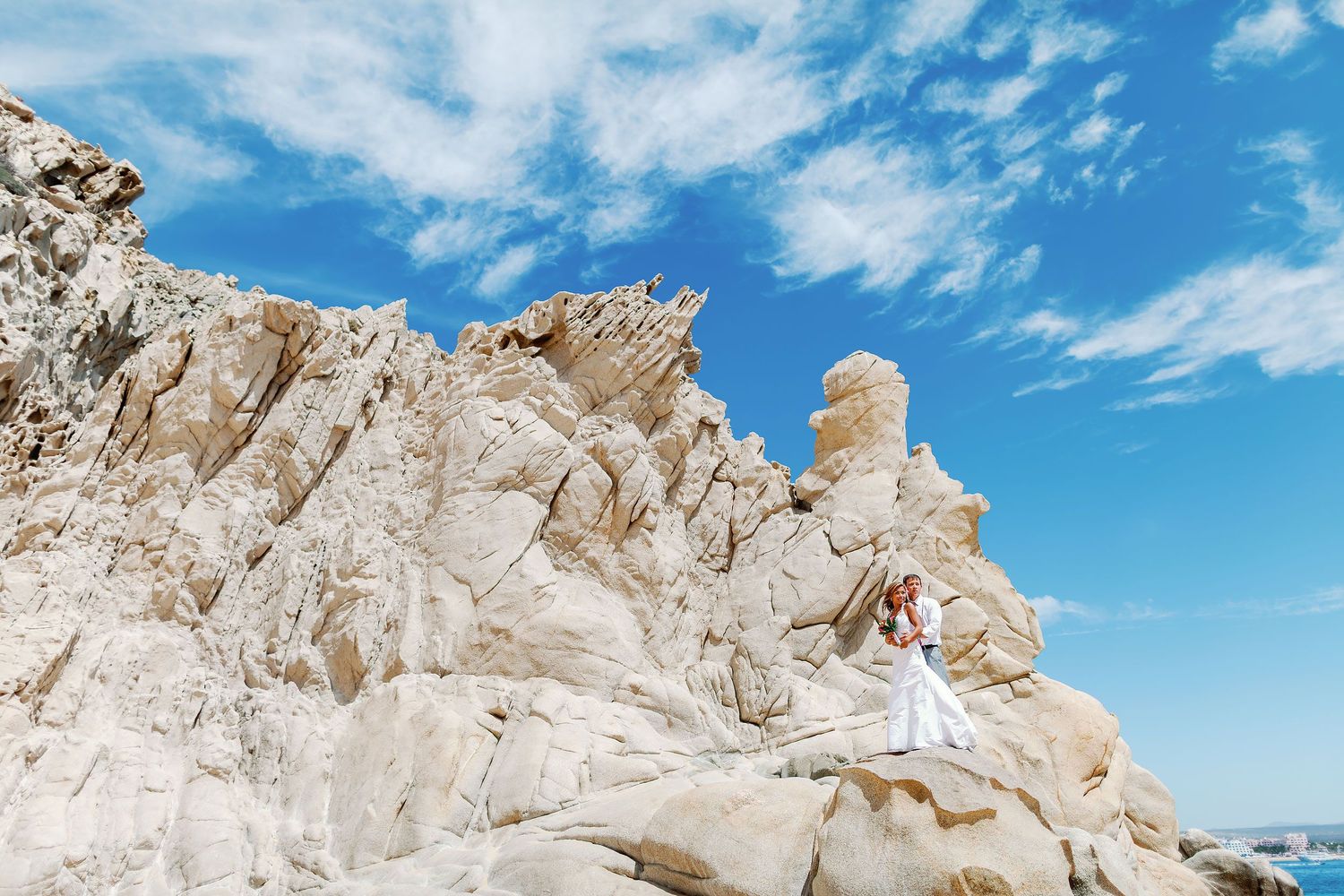 Creative wedding portrait in Cabo San Lucas featuring a bride and groom surrounded by iconic Baja California rock formations