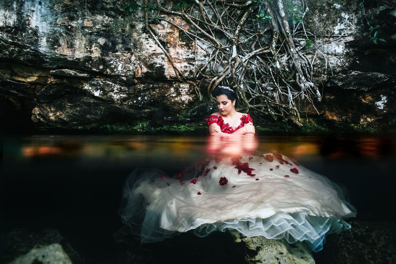 Quinceañera portrait in a Playa del Carmen cenote featuring an elegant gown, crystal-clear water, and jungle scenery.