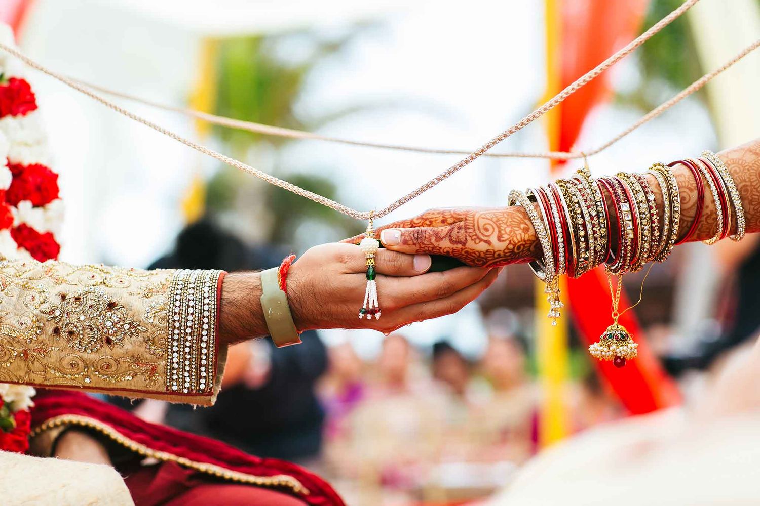 Close-up of traditional Hindu wedding ceremony ritual at Hard Rock Riviera Maya featuring bride’s mehndi hands, bridal bangles, and sacred w