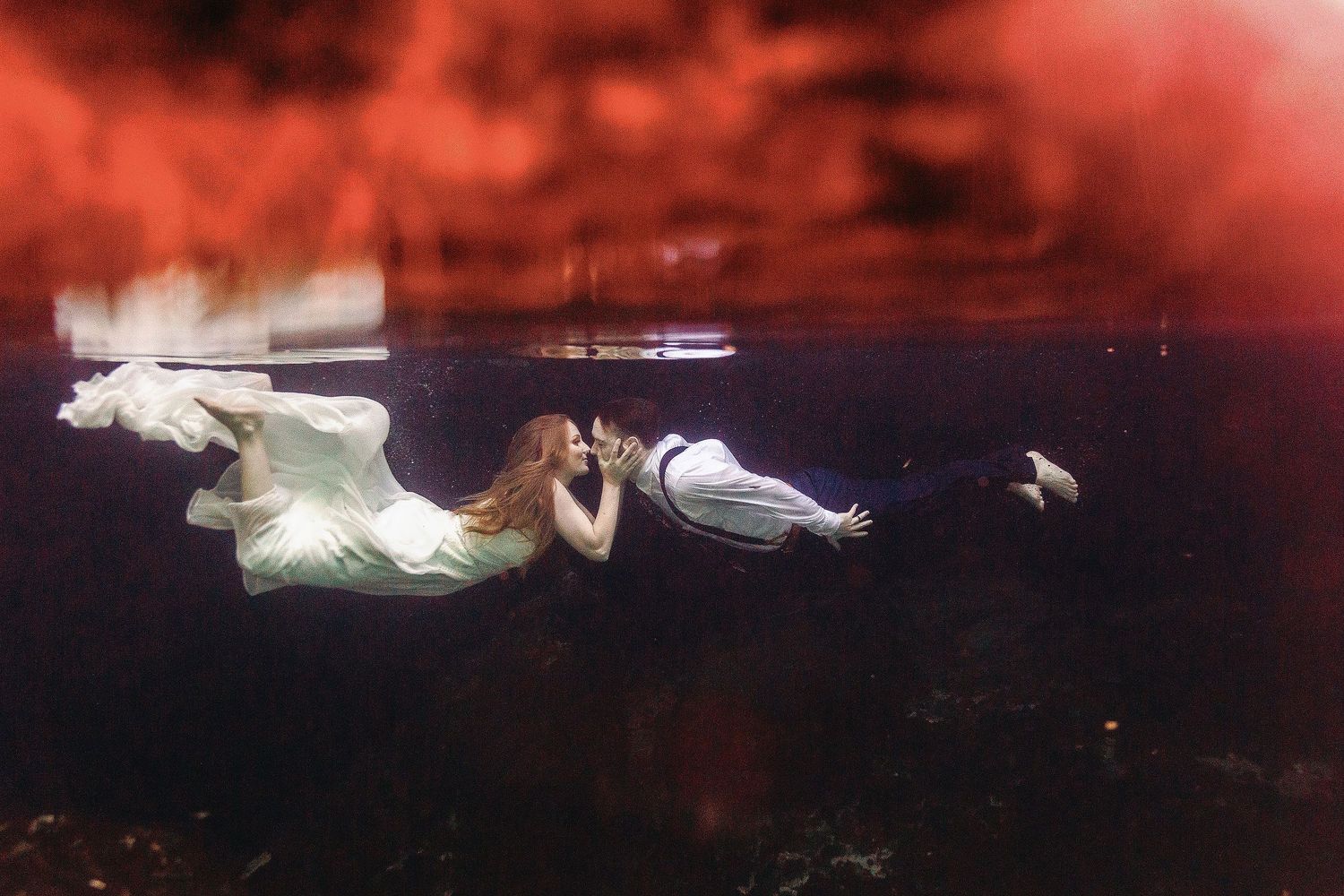 Nicole and Thomas swimming toward a kiss during their underwater wedding photography session at Cenote Azul near Playa del Carmen.