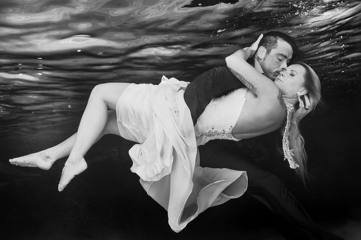 Black-and-white underwater portrait of Carly in Scott’s arms