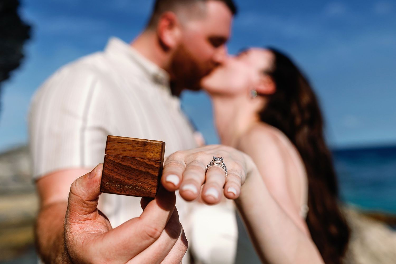 Alexia shows her engagement ring while she and Sam kiss beside the ocean in Isla Mujeres.
