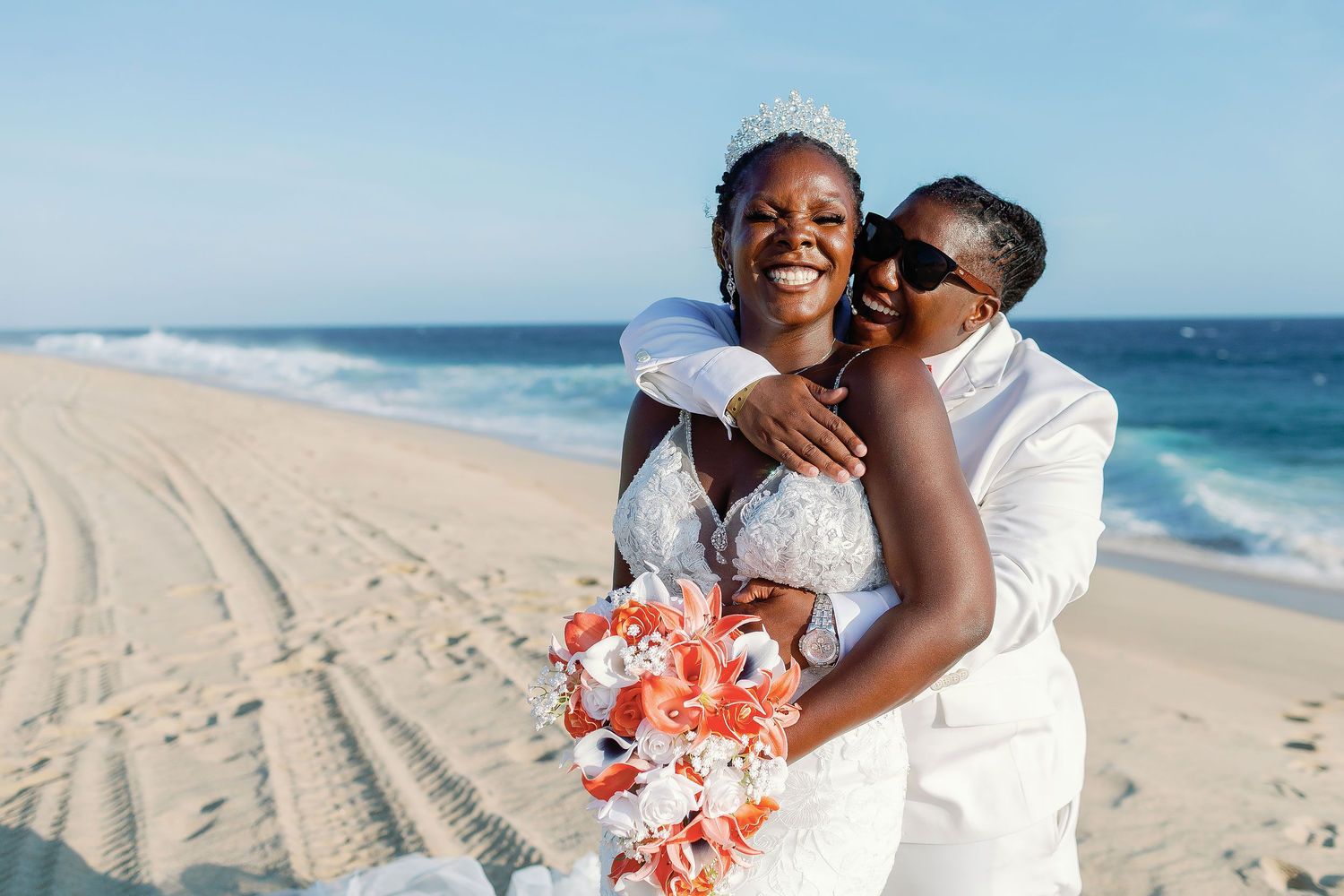 Joyful newlywed couple embracing on the beach at Hard Rock Los Cabos during a luxury same-sex destination wedding in Baja California Sur.