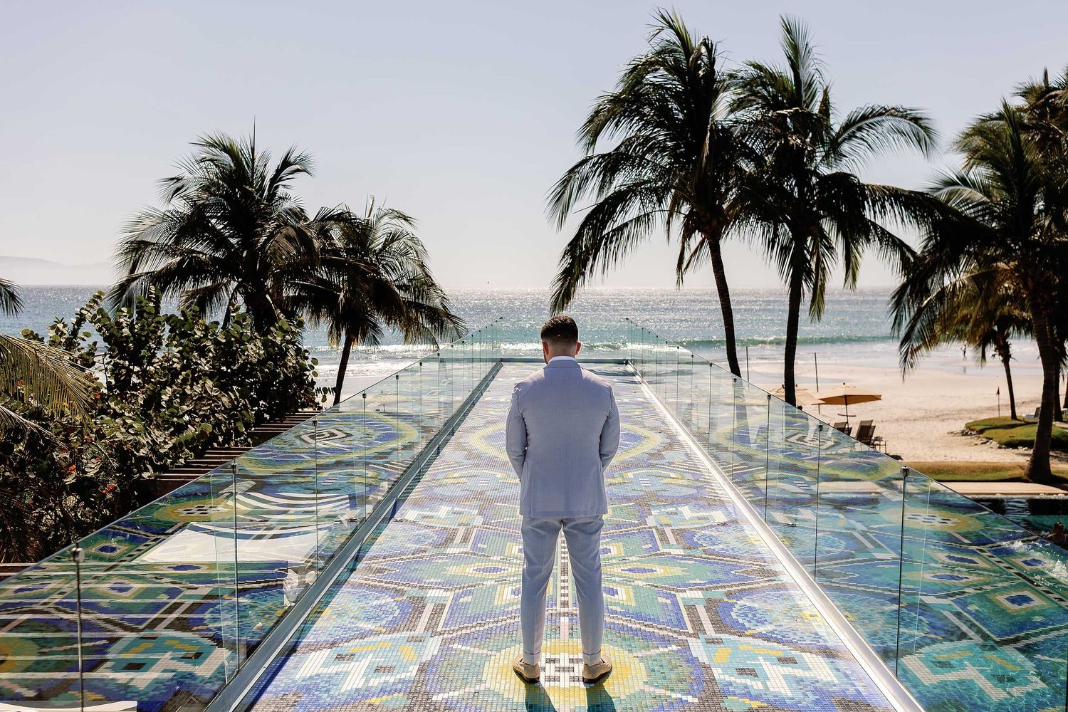 Groom portrait overlooking the Pacific Ocean from the iconic mosaic sky bridge at W Punta de Mita during a luxury destination wedding in Mex