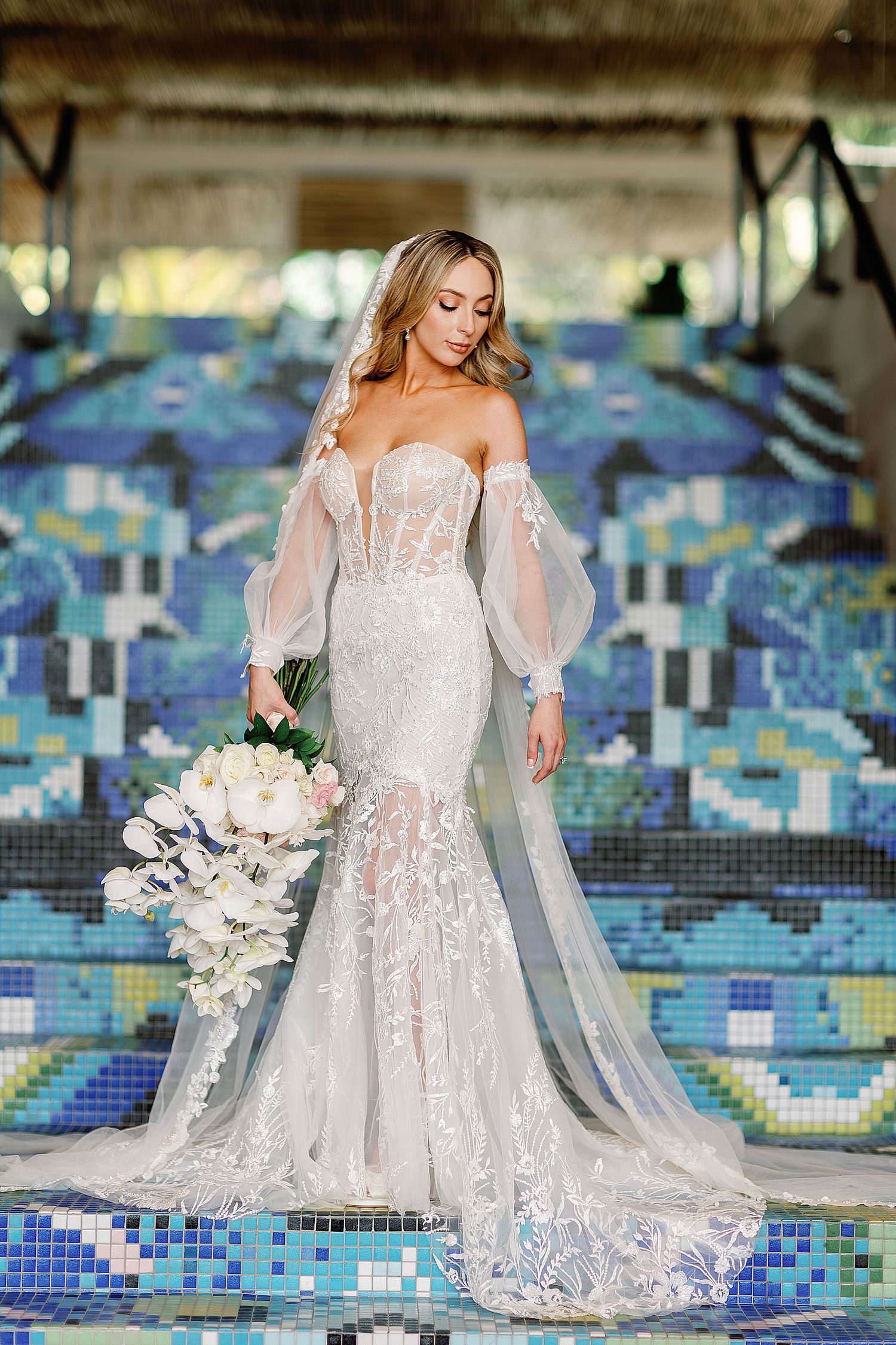 Elegant bridal portrait at W Punta de Mita featuring a lace wedding gown, cascading orchid bouquet, and colorful Mexican-inspired architectu