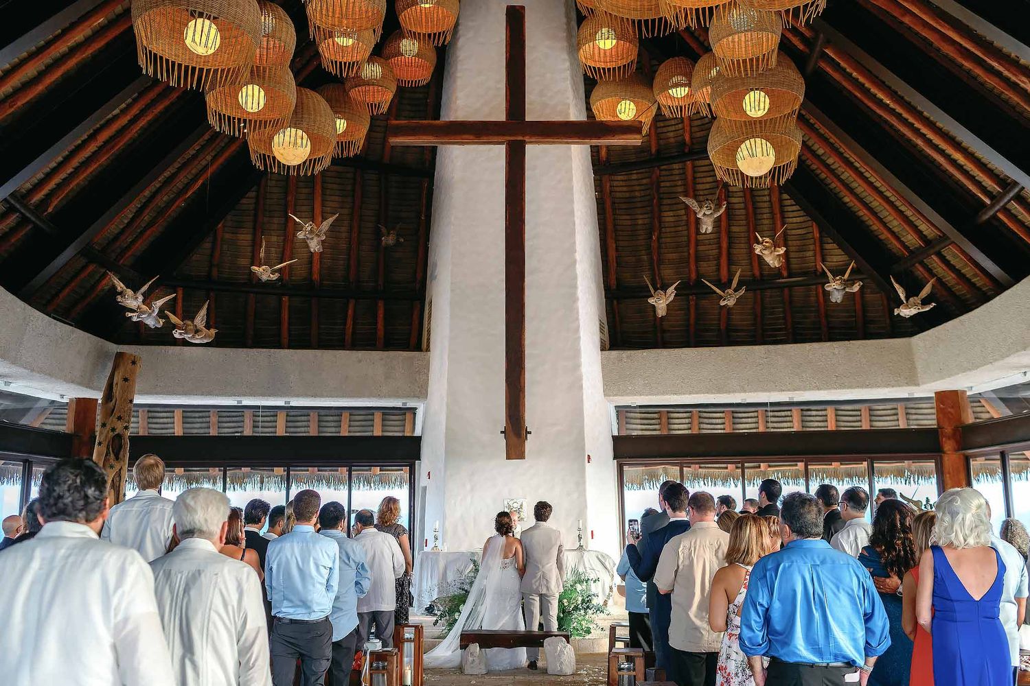 Catholic wedding ceremony at All Ángeles Chapel in Hotel Xcaret Mexico with wooden cross and guests, Riviera Maya destination venue